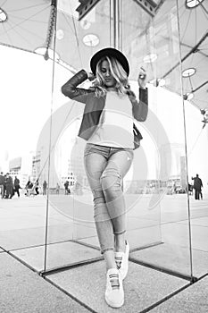 Girl in hat, jacket, jeans, sneakers in la defense, paris