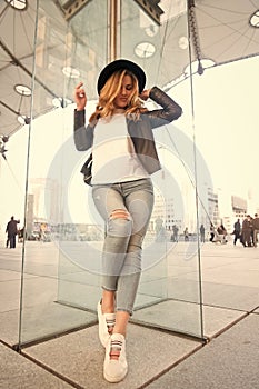 Girl in hat, jacket, jeans, sneakers in la defense, paris