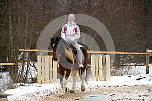 Girl in a hat and jacket riding a horse