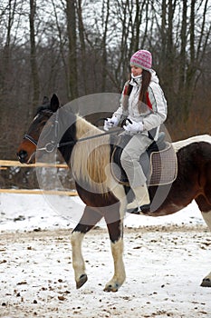 Girl in a hat and jacket riding a horse