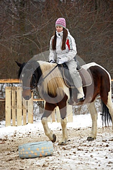 Girl in a hat and jacket riding a horse