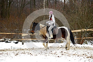 Girl in a hat and jacket riding a horse