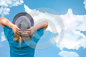 Girl in hat looks at big dove bird in cloud shape that soars in blue sky. Concept of love, romance and happy relations. Pure clear