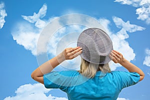 Girl in hat looks at dove birds in cloud shape soars in blue sky. Concept of love, romance and happy relations. Valentine day or