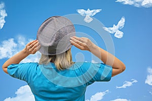 Girl in hat looks at dove birds in cloud shape soars in blue sky. Concept of love, romance and happy relations. Valentine day or