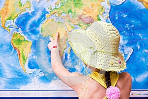 Girl in a hat points to a world map with a finger