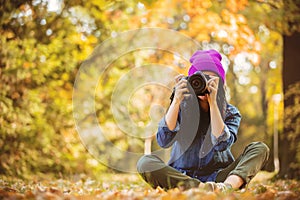 Girl in hat with professional camera on fall season park