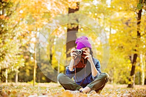 Girl in hat with professional camera on fall season park