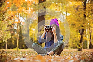 Girl in hat with professional camera on fall season park