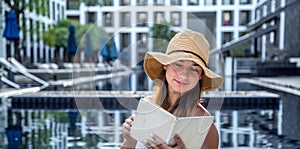 Girl in a hat reading a book by the pool