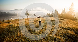 Girl with hat run with happiness on top of a mountain in autumn sunrise.