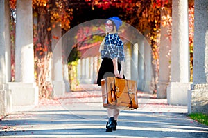 Girl in hat and shirt with suitcase in red grape alley