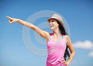 Girl in hat showing direction on the beach
