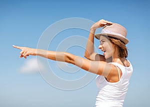 Girl in hat showing direction on the beach