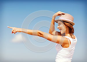 Girl in hat showing direction on the beach