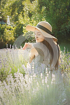 The girl in the hat sit in the middle of a lavender field