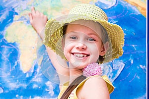 The girl in the hat is smiling and showing the world map