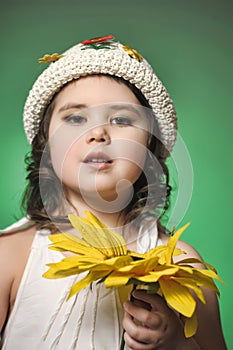 Girl in a hat in the studio on a green background with sunflower