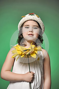 Girl in a hat in the studio on a green background with sunflower