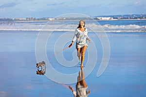 Girl have fun with dachshund dog, run by sea beach