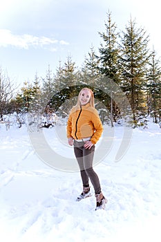 Girl have yellow jacket in winter outside on fir trees background. Young woman walks through snow-covered park or forest