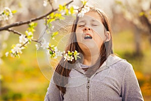 Girl having allergy outdoor. The girl sneezes. Selective focus photo