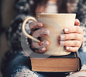 Girl having a break with cup of fresh coffee after reading books or studying