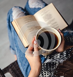 Girl having a break with cup of fresh coffee after reading books or studying and