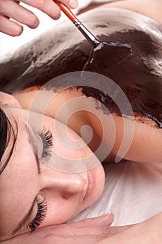 Girl having chocolate bodyl mask . photo