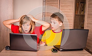 Girl having a computer problem. Cute children using laptops at h