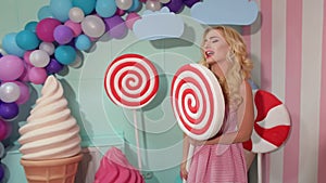 Girl having fun with big plastic candy in Studio.