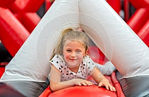 Girl having fun among inflatable obstacles jumping playground