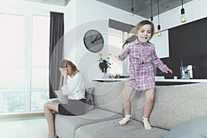 Girl Having Fun Jumping on Sofa when Mother Upset