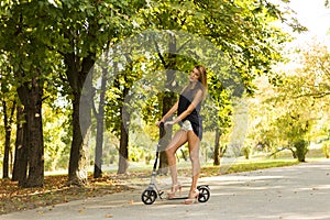 Girl having fun on a kick scooter on a park alley 