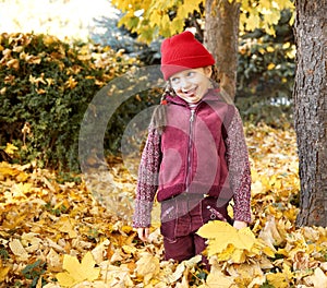 Girl having fun an make faces in autumn forest, yellow leaves and trees on background