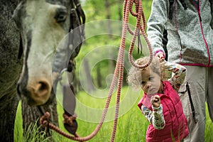 Girl having fun with mother and horse in the woods, young pretty girl with blond curly hair, freedom, joy, movement, outdoor,