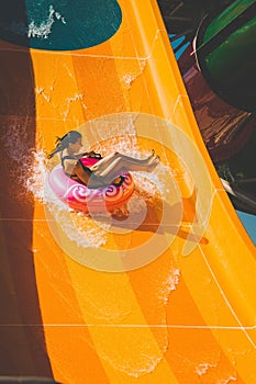 Girl having fun on the orange water slide in aqua park