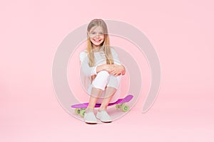 Girl having fun with penny board pink background. Kid adorable child long hair adore ride penny board. Ride penny board