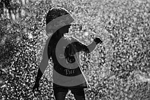 Girl is having fun in water in park, hot summer in garden, girl running in water drops,happy and cheerful girl enjoying cold water