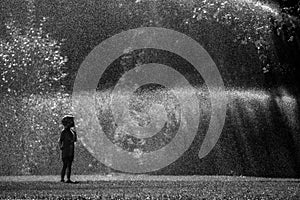 Girl is having fun in water in park, hot summer in garden, girl running in water drops,happy and cheerful girl enjoying cold water