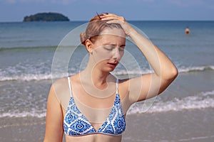 Girl having headache on seaside. Suffering woman on sunny beach. Woman sunstroke by sea. Hot sun danger.