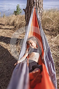 Girl having rest in hammock in wild forest during local vacation, unity with nature, digital detox