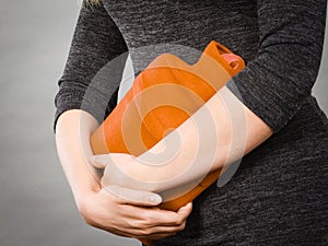 Girl having stomach ache, holding hot water bottle