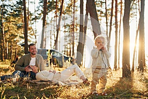 Girl is having a walk. Happy family of father, mother and little daughter is in the forest