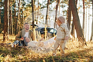 Girl is having a walk. Happy family of father, mother and little daughter is in the forest