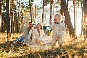 Girl is having a walk. Happy family of father, mother and little daughter is in the forest