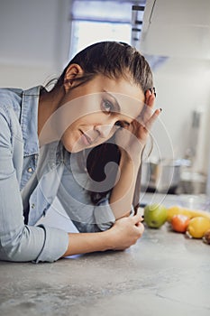 Girl with headache leaning on a kitchen countertop