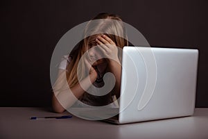 Girl with headache sitting at the desk and doing homework . Tired child using computer.