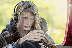 Girl with headphones on a bus. Activity on a journey. Selective focus. Travel and modern technology concept