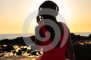 Girl in headphones listening to music in the city at sunset.